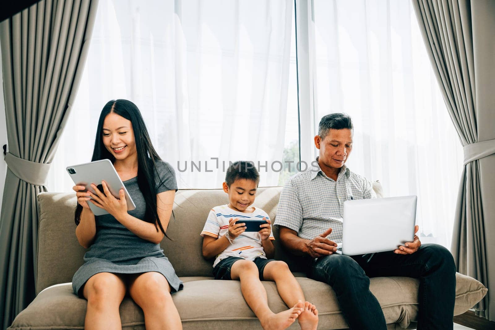 At home an Asian family's device obsession overshadows bonding time. Parents and kids immersed in gadgets illustrate the effects of excessive internet usage. ignores togetherness