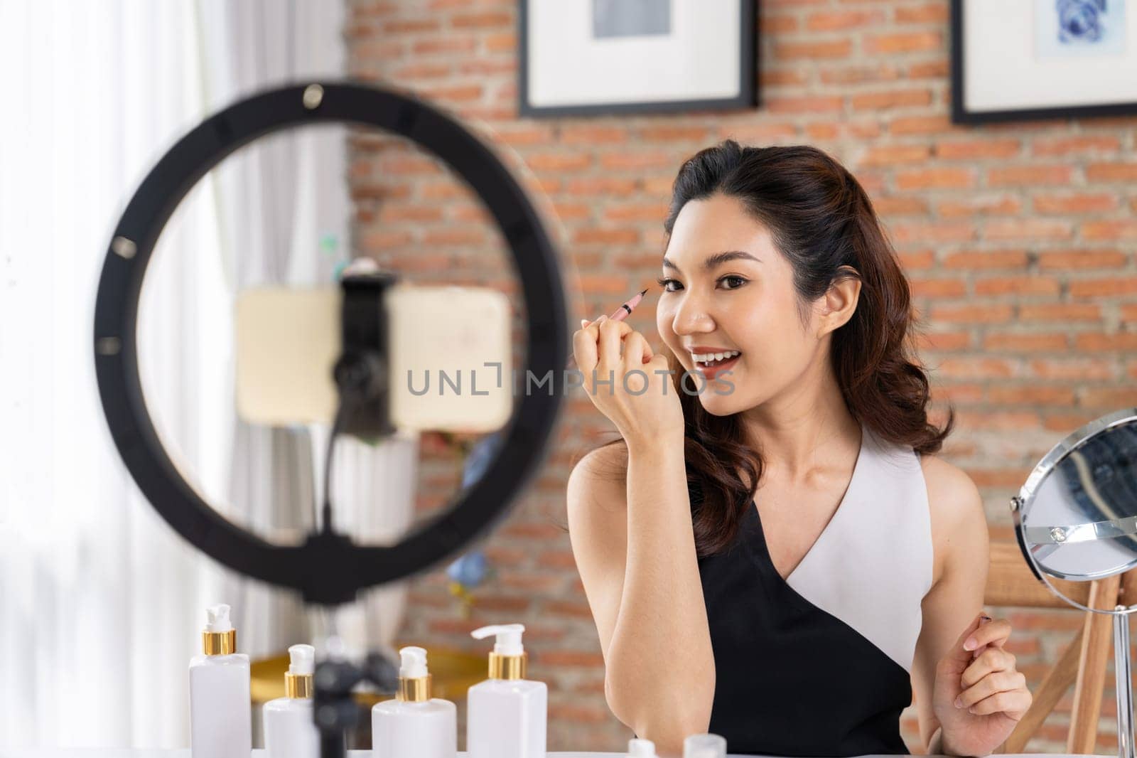 Asian Woman influencer shoot live streaming vlog video review makeup uttermost social media or blog. Happy young girl with cosmetics studio lighting for marketing recording session broadcasting online