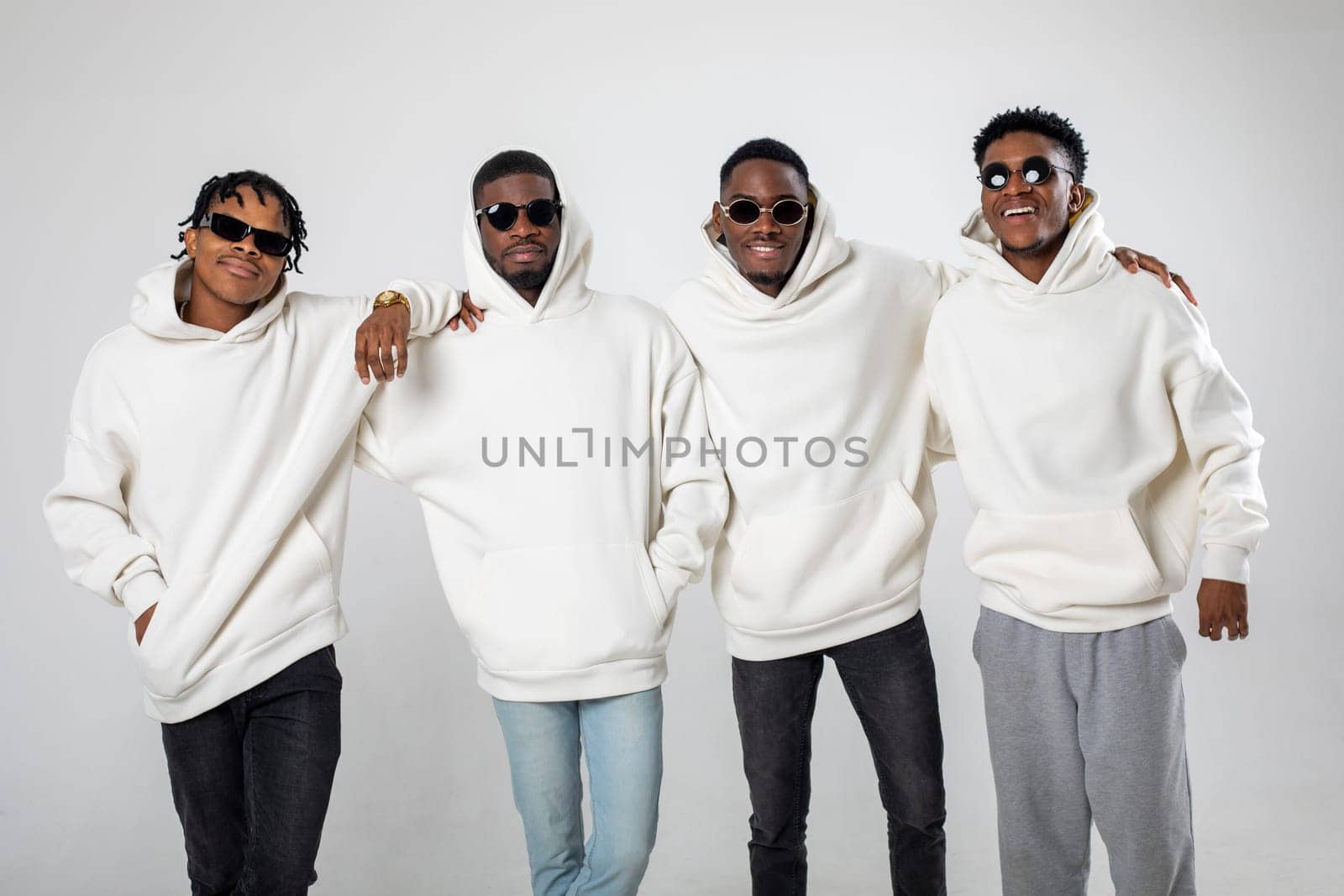 Group of African American guys in brown hoodies posing on a white background wearing sunglasses by Freeman_Studio