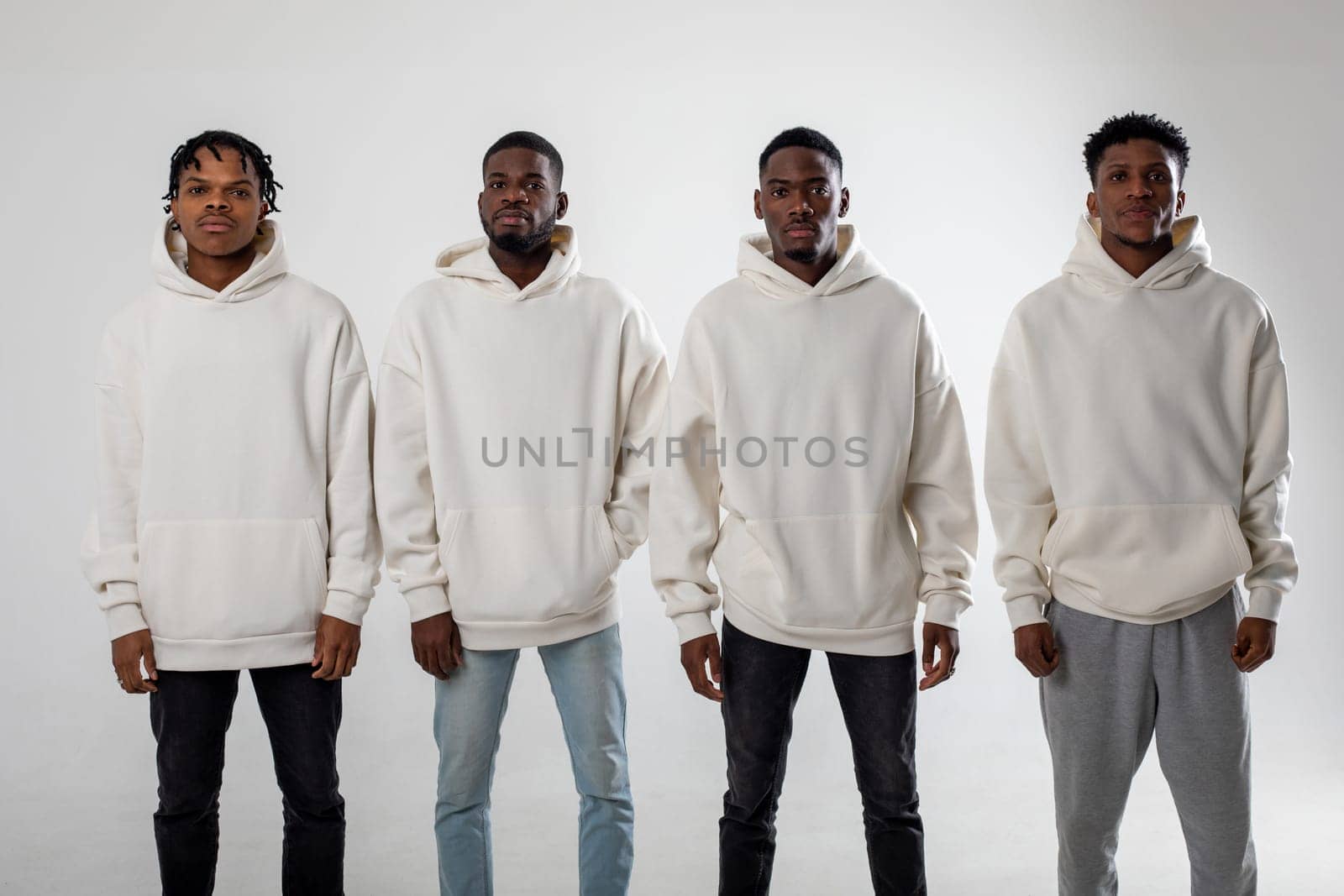 Group of African American guys in brown hoodies posing on a white background wearing sunglasses. High quality photo