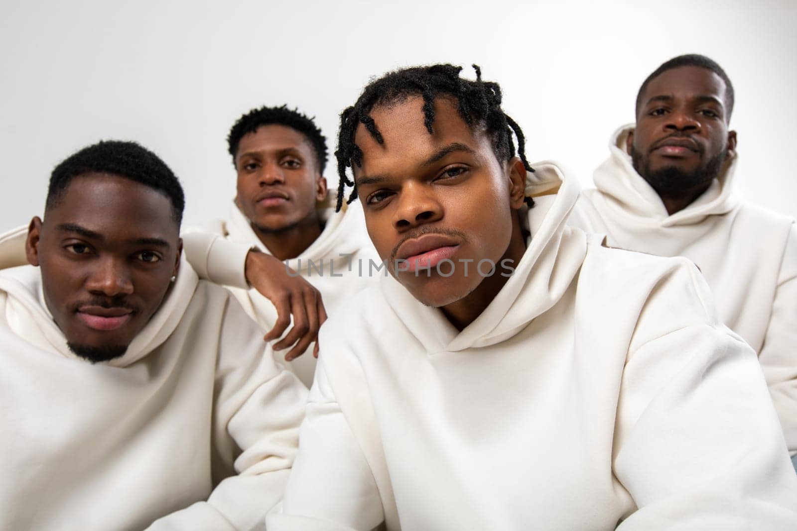 Group of African American guys in brown hoodies posing on a white background by Freeman_Studio
