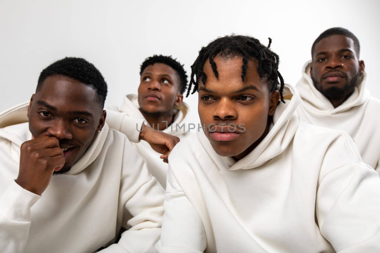 Group of African American guys in brown hoodies posing on a white background by Freeman_Studio