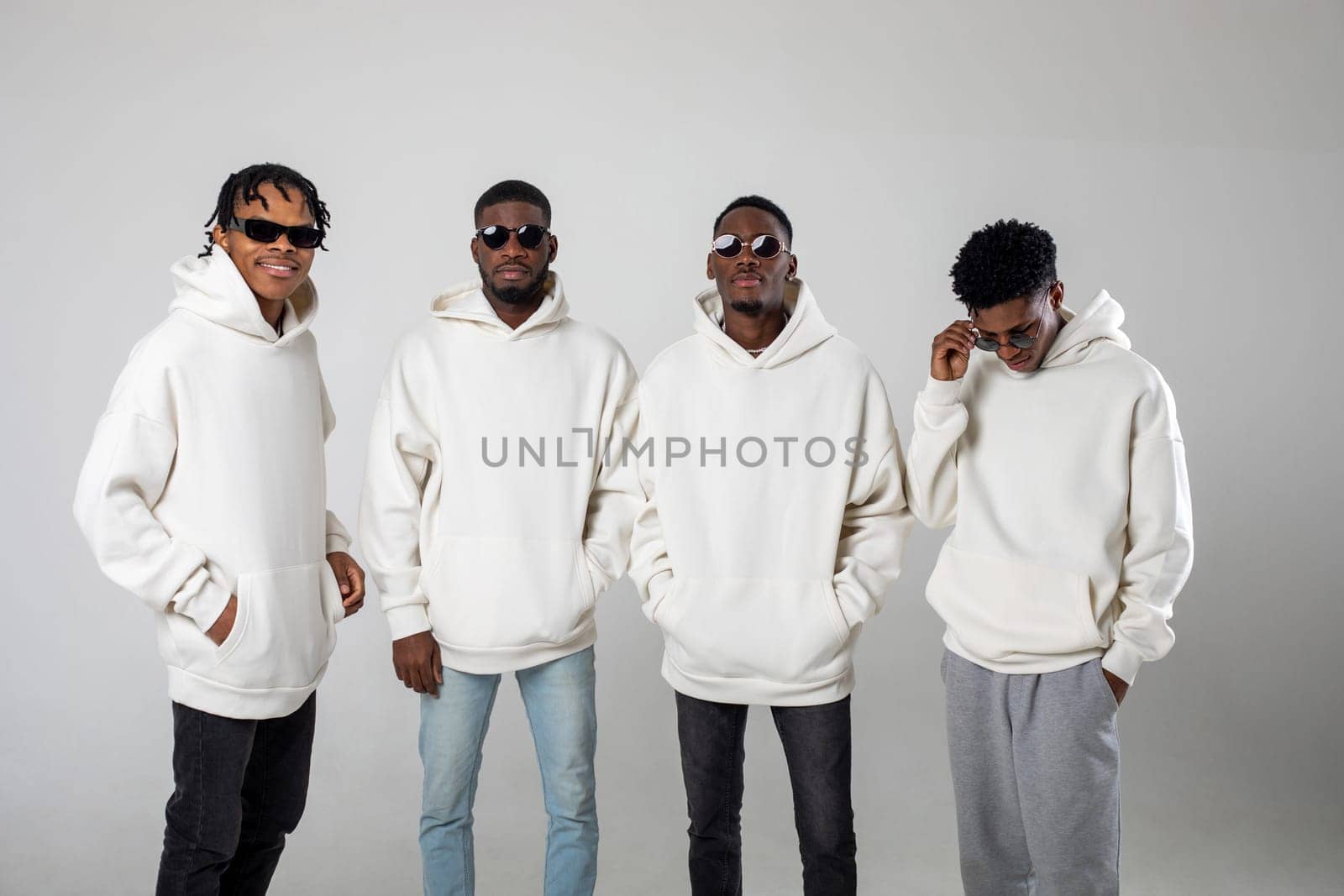 Group of African American guys in brown hoodies posing on a white background wearing sunglasses by Freeman_Studio