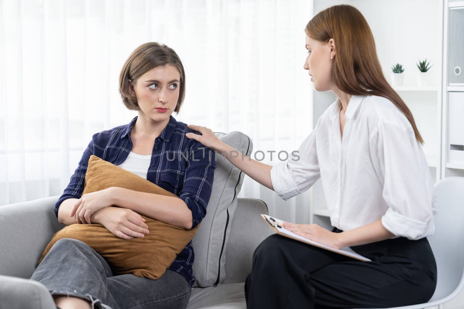 Sad PTSD woman patient in utmost therapy for mental health with psychologist, depression or grief after life failure. Frustrated trauma young woman talking to a psychologist about emotion in clinic