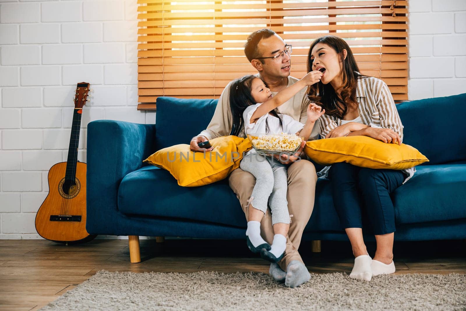 family finds relaxation and joy while watching TV with popcorn at home. father mother son daughter and schoolgirl share moments of happiness creating cherished memories during their quality time.