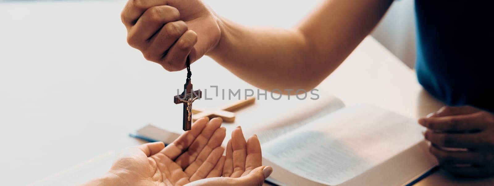 Close-up women prayer deliver holy bible book and holy cross to young believer. Spreading religion symbol. Concept of hope, religion, christianity and god blessing. Warm background. Burgeoning.