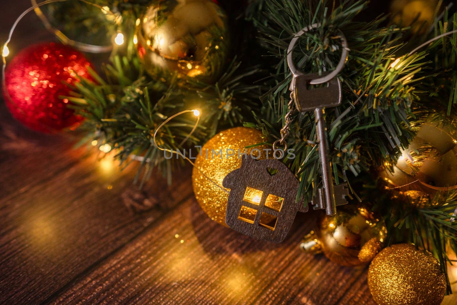 Gift key house with a keychain backdrop of Christmas tree. Building, design, project, moving to new house, mortgage, rent and purchase real estate. A gift for New Year, Christmas by Matiunina