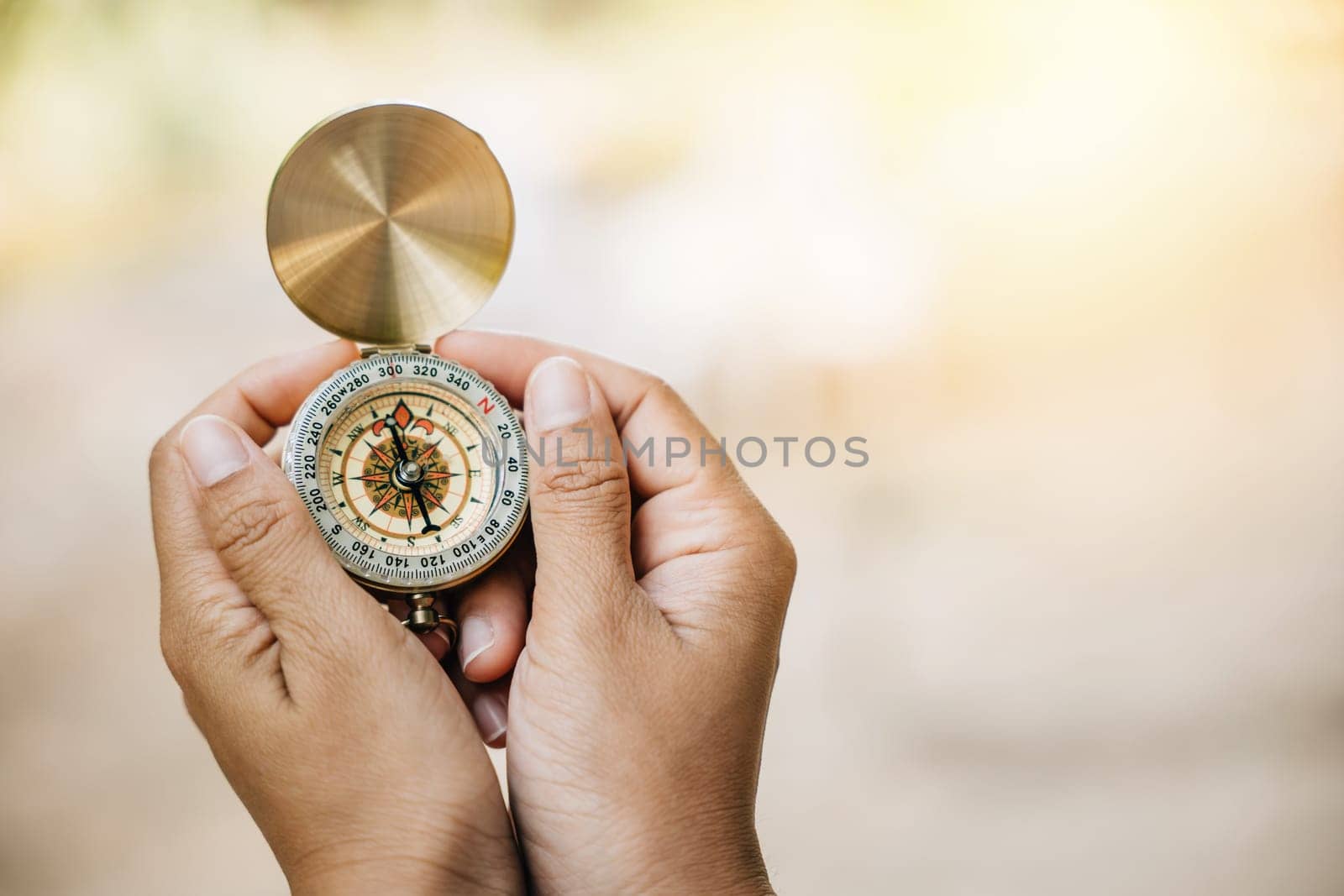 Close-up of a woman using a compass during her forest hike highlighting guidance and exploration. Her hand holds the compass amidst nature's beauty. by Sorapop