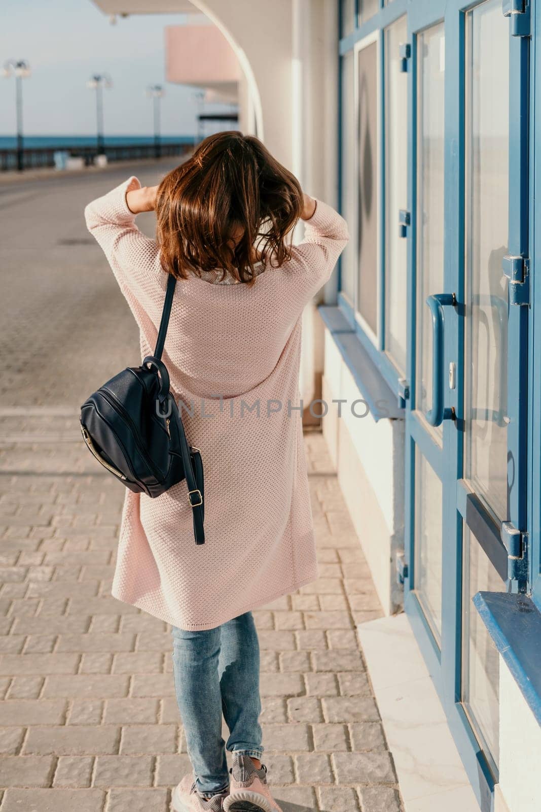 Woman travel sea. Young Happy woman in a long red dress posing on a beach near the sea on background of volcanic rocks, like in Iceland, sharing travel adventure journey