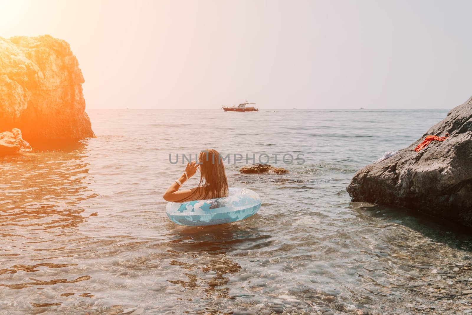 Woman summer sea. Happy woman swimming with inflatable donut on the beach in summer sunny day, surrounded by volcanic mountains. Summer vacation concept