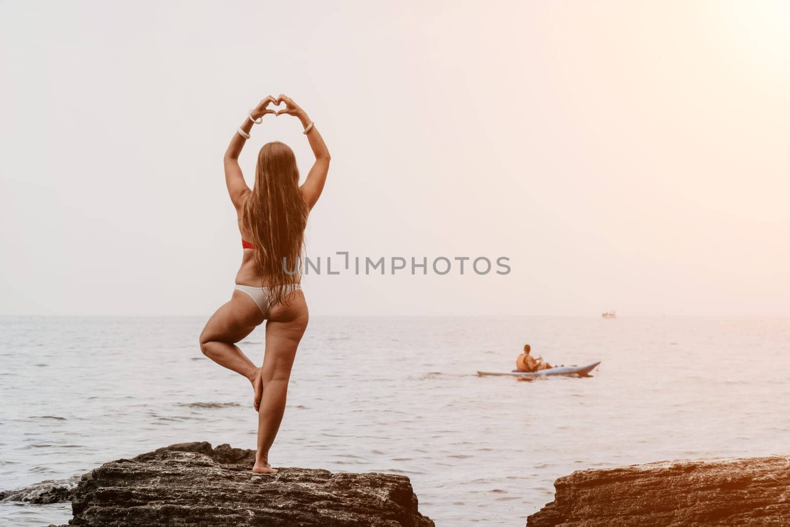 Woman meditating in yoga pose silhouette at the ocean, beach and rock mountains. Motivation and inspirational fit and exercising. Healthy lifestyle outdoors in nature, fitness concept.