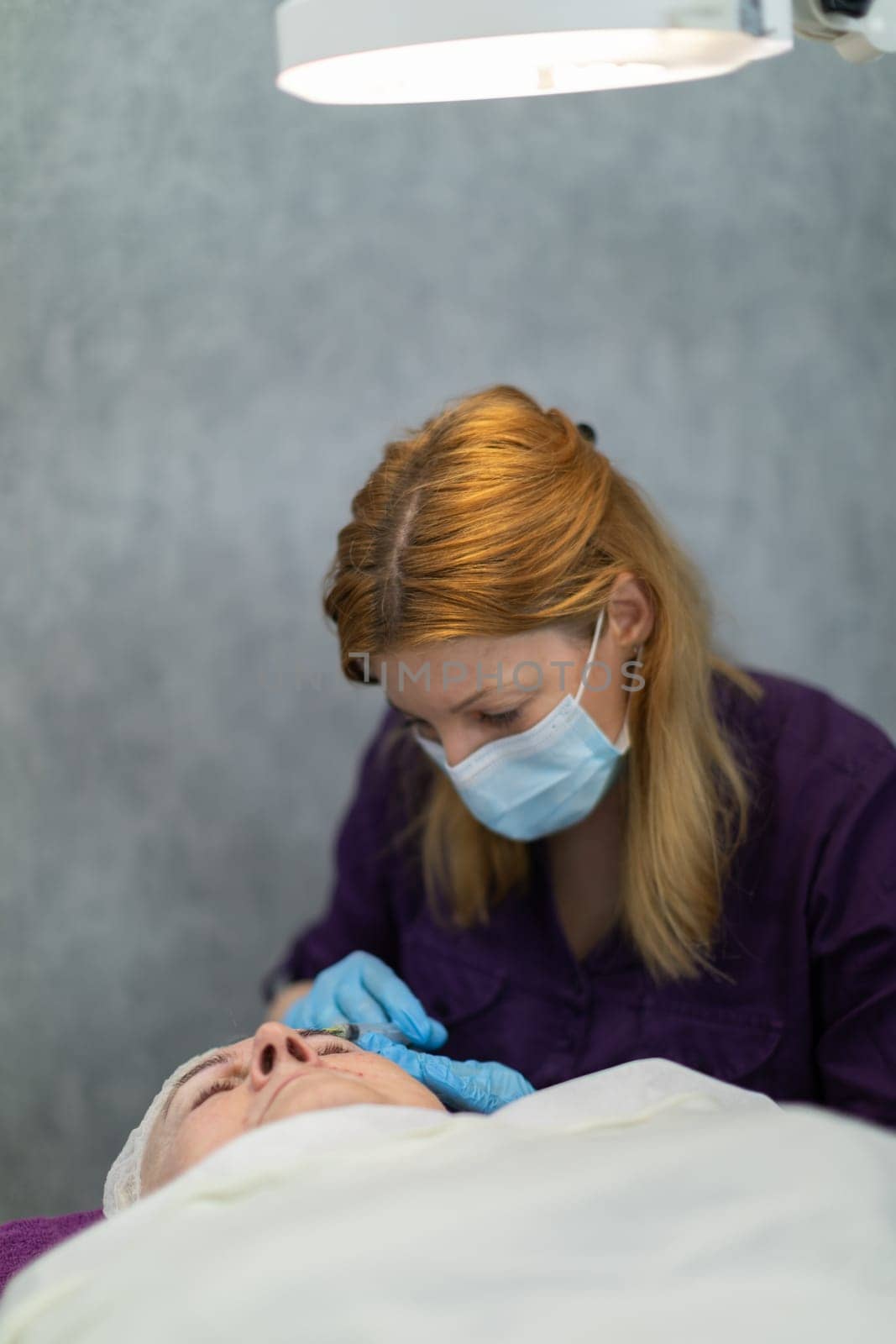 The medical lamp accurately illuminates the treatment field. The patient lies down while the doctor performs subcutaneous injections.