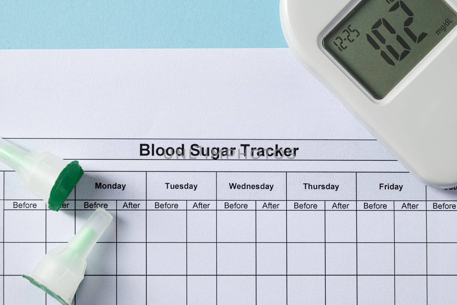 Top view of glucometer, lancet pen, strips and blood sugar tracker on blue background. diabetes test kit