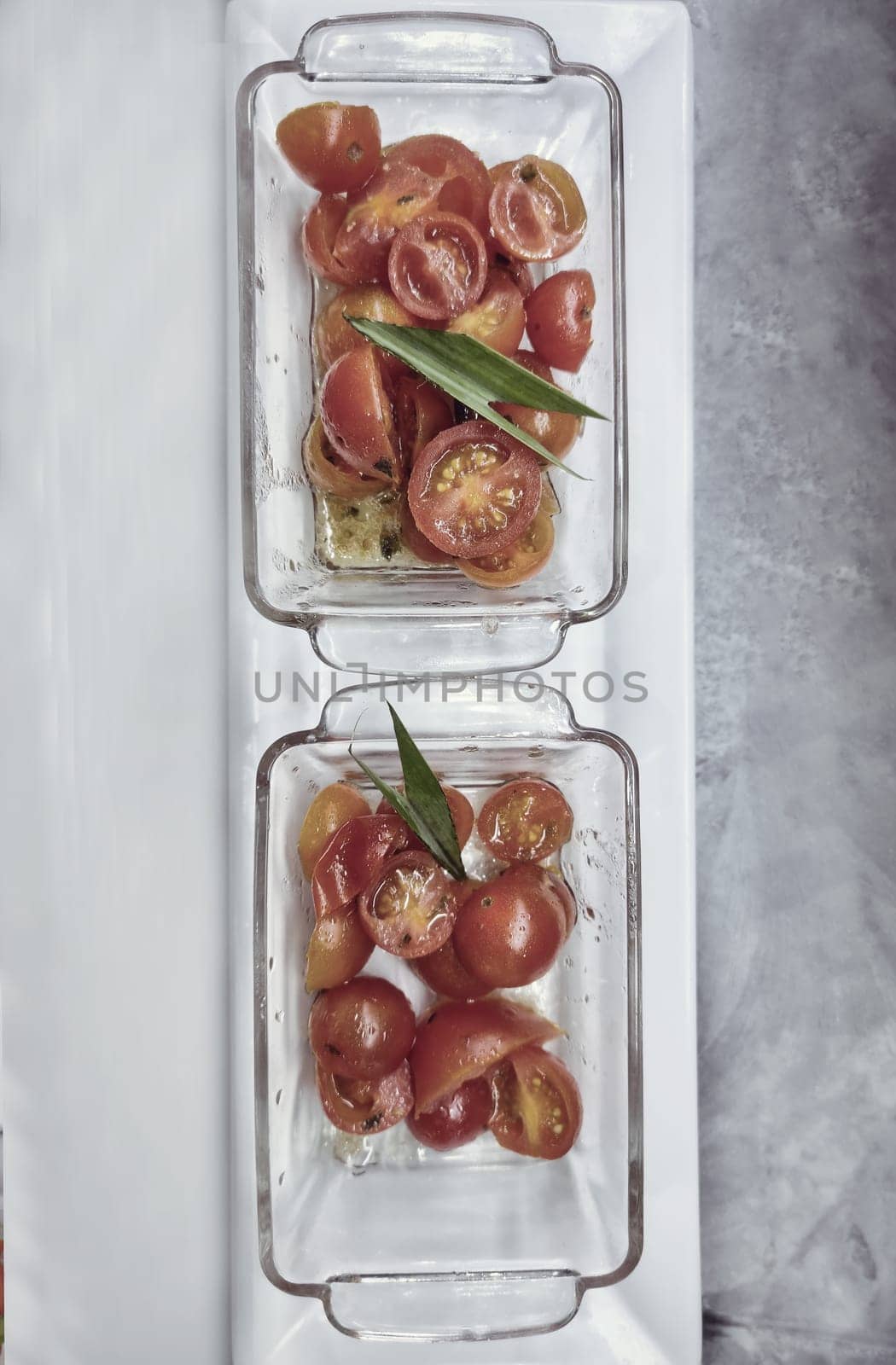 Delicious appetizer of cherry tomatoes in glass plates on a white background