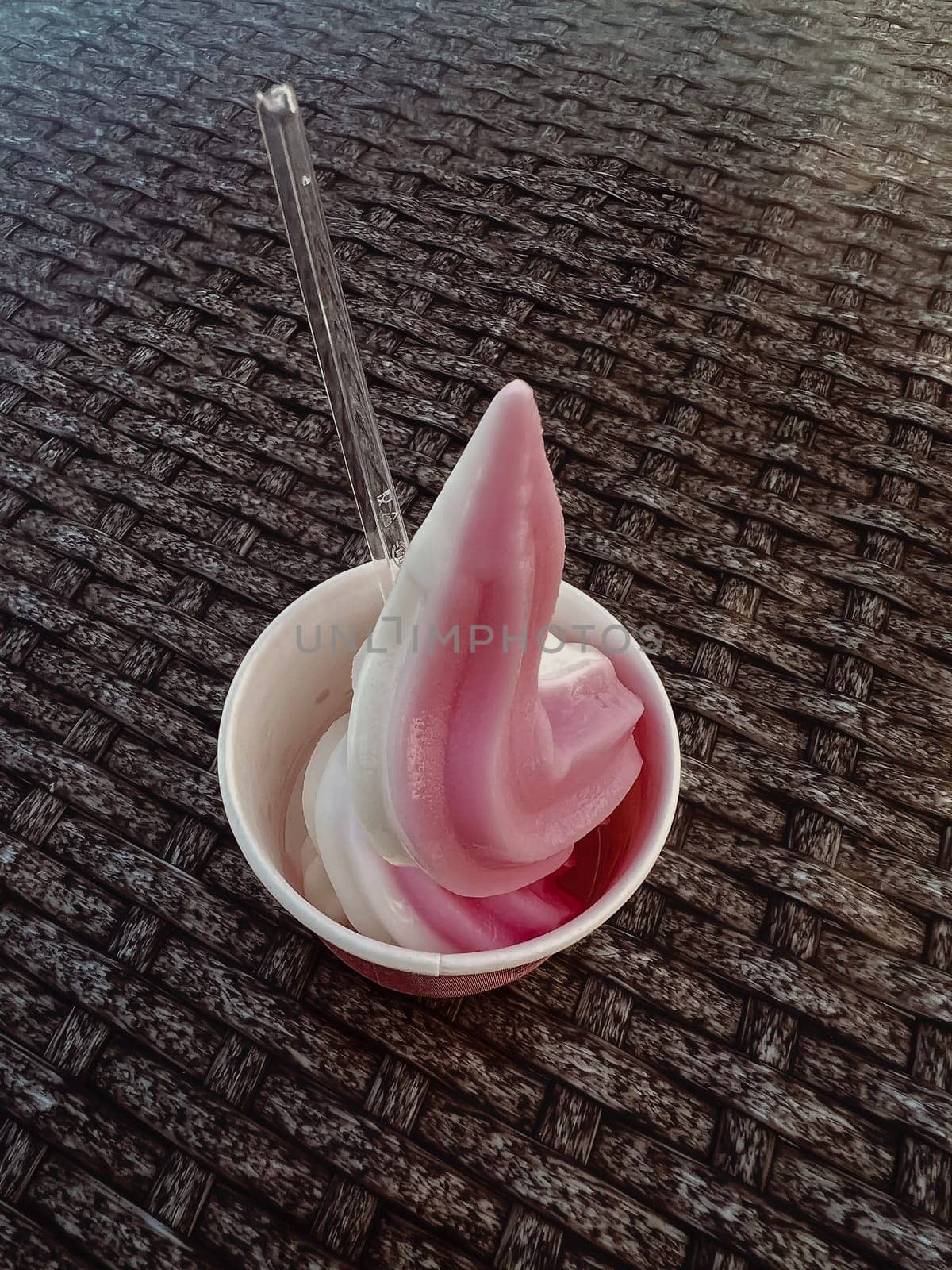 On the table in a cup is a beautifully decorated delicious creamy fruit ice cream. Blurred background.