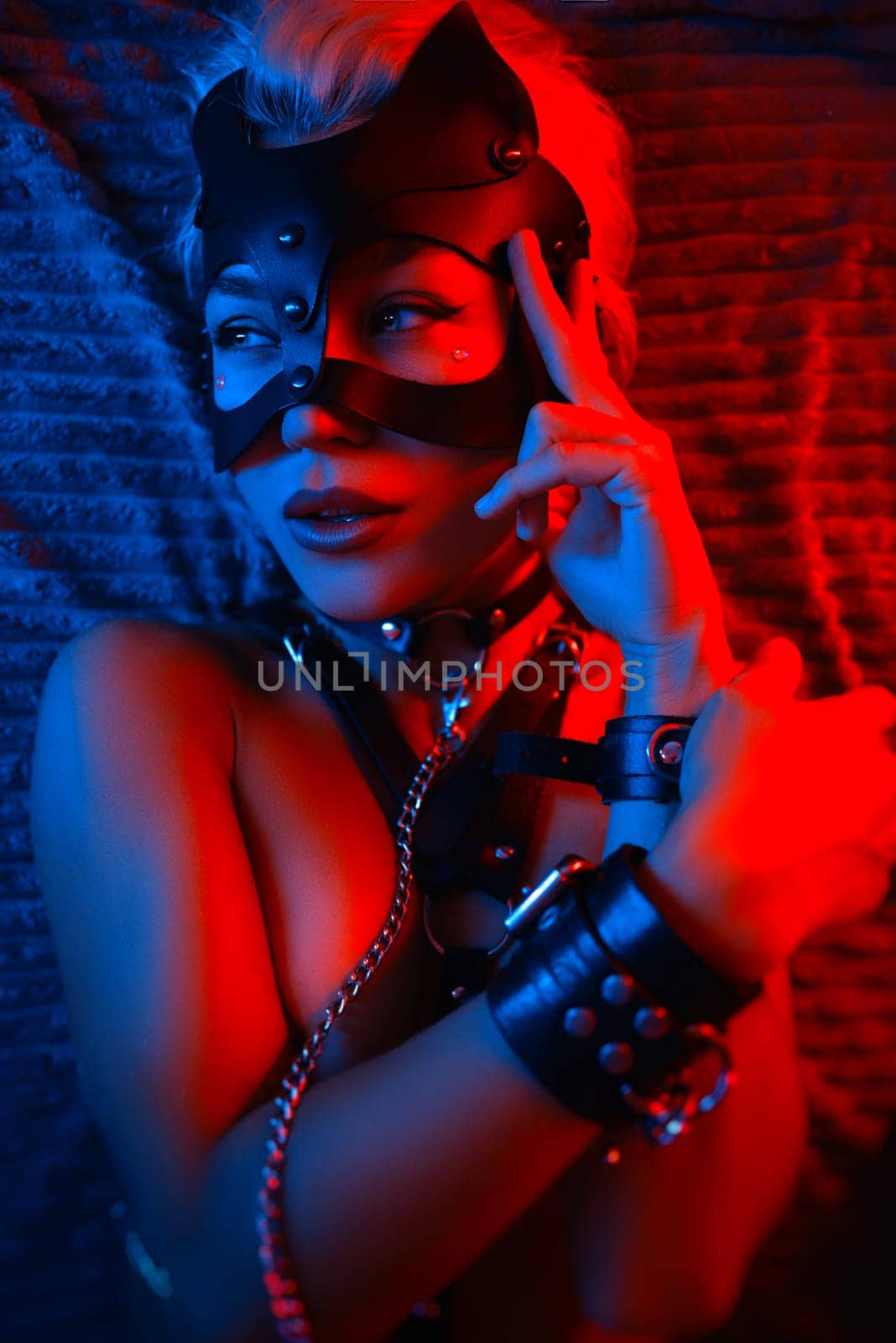 portrait of a sexy girl in leather cat mask and bdsm accessories with beautiful lips and eyes with emotions in neon light