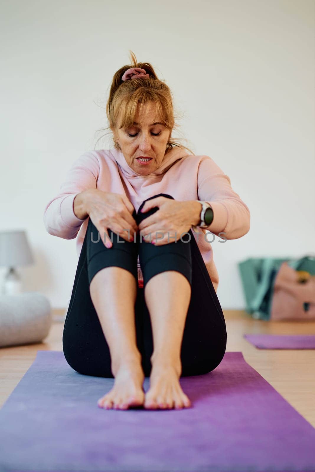 In a sunlit space, a senior woman gracefully practices rejuvenating yoga, focusing on neck, back, and leg stretches, embodying serenity and well-being by dotshock