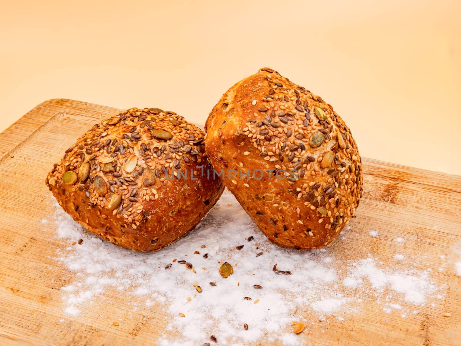 Studio shot with whole grain buns arranged on a board with flour fresh for breakfast