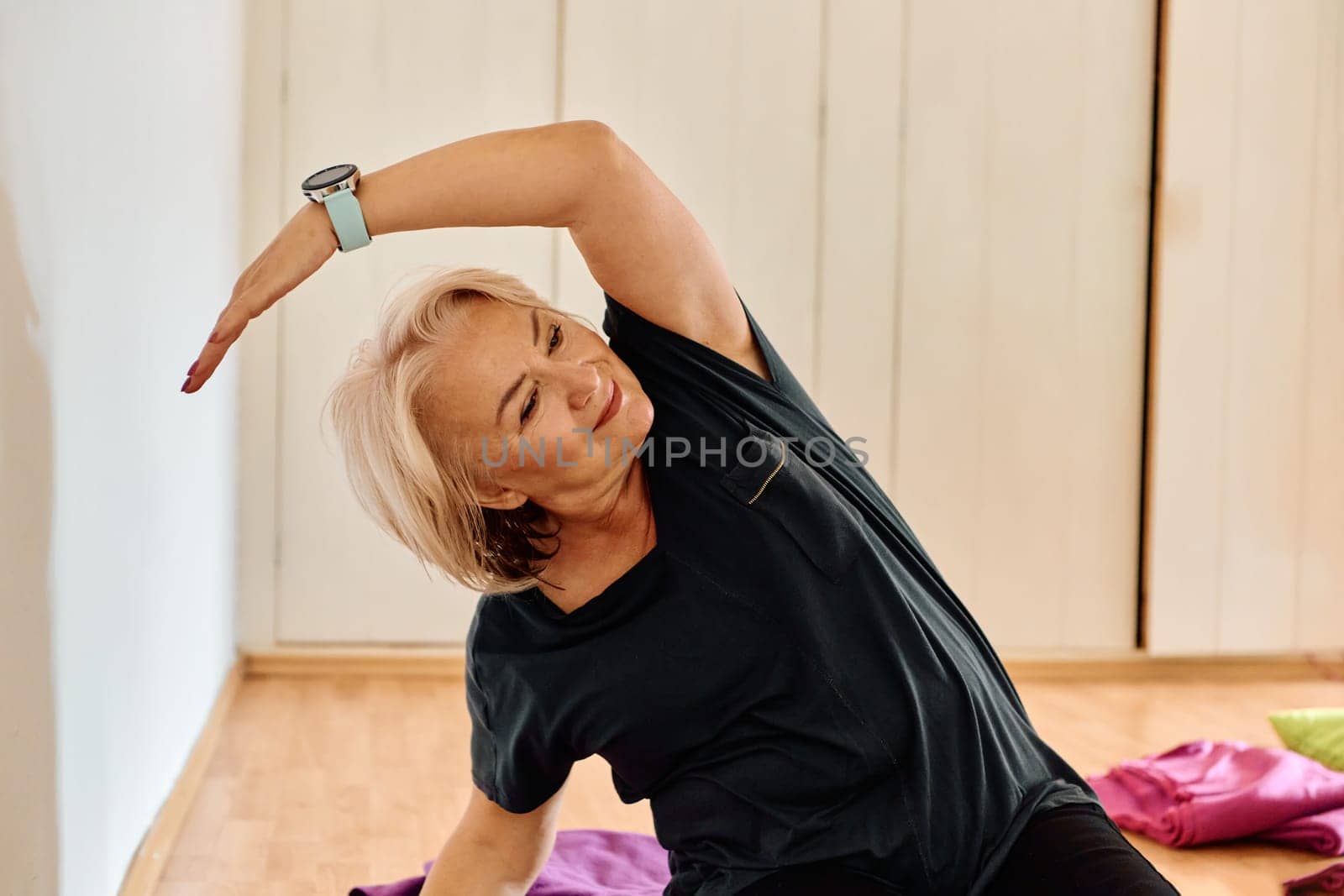 In a sunlit space, a senior woman gracefully practices rejuvenating yoga, focusing on neck, back, and leg stretches, embodying serenity and well-being.