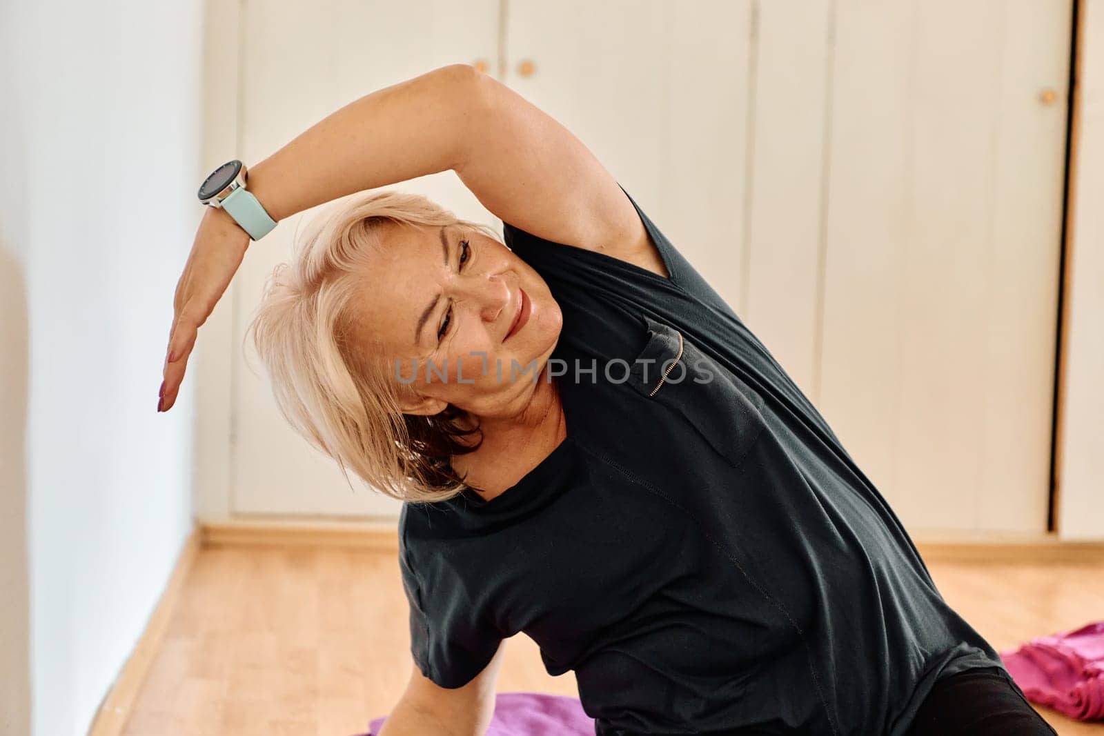 In a sunlit space, a senior woman gracefully practices rejuvenating yoga, focusing on neck, back, and leg stretches, embodying serenity and well-being.