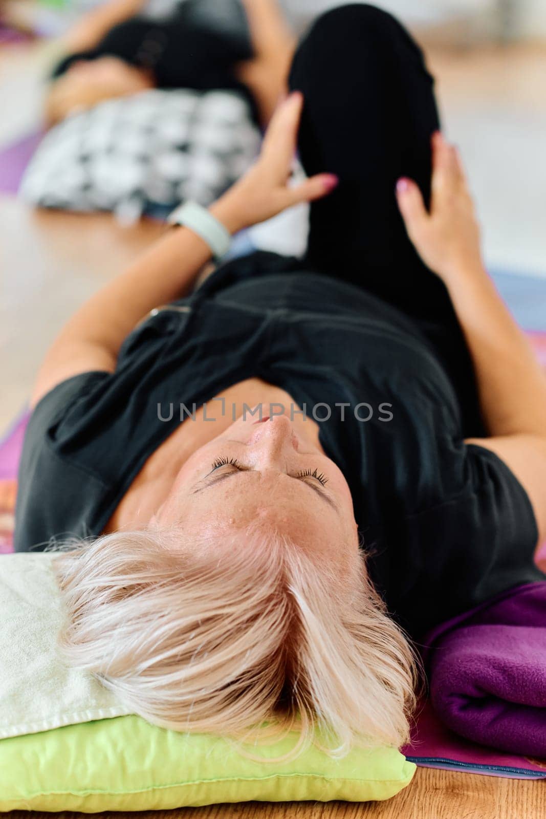 In a sunlit space, a senior woman gracefully practices rejuvenating yoga, focusing on neck, back, and leg stretches, embodying serenity and well-being by dotshock