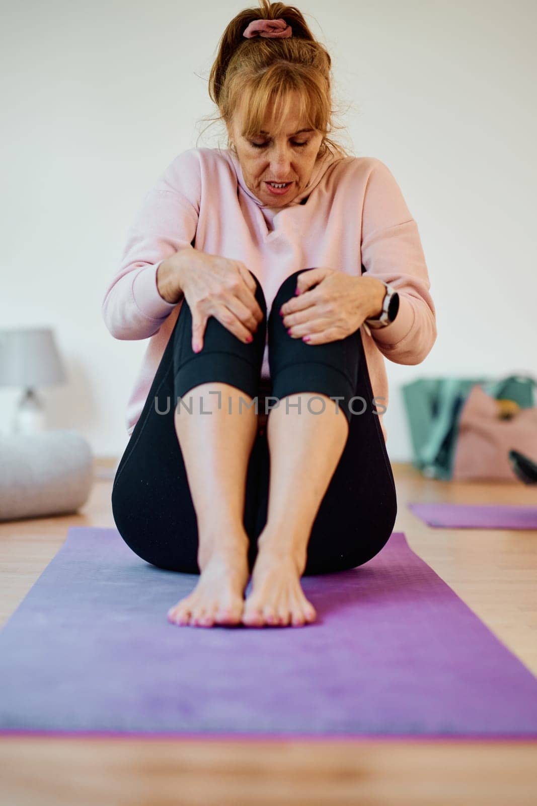 In a sunlit space, a senior woman gracefully practices rejuvenating yoga, focusing on neck, back, and leg stretches, embodying serenity and well-being.