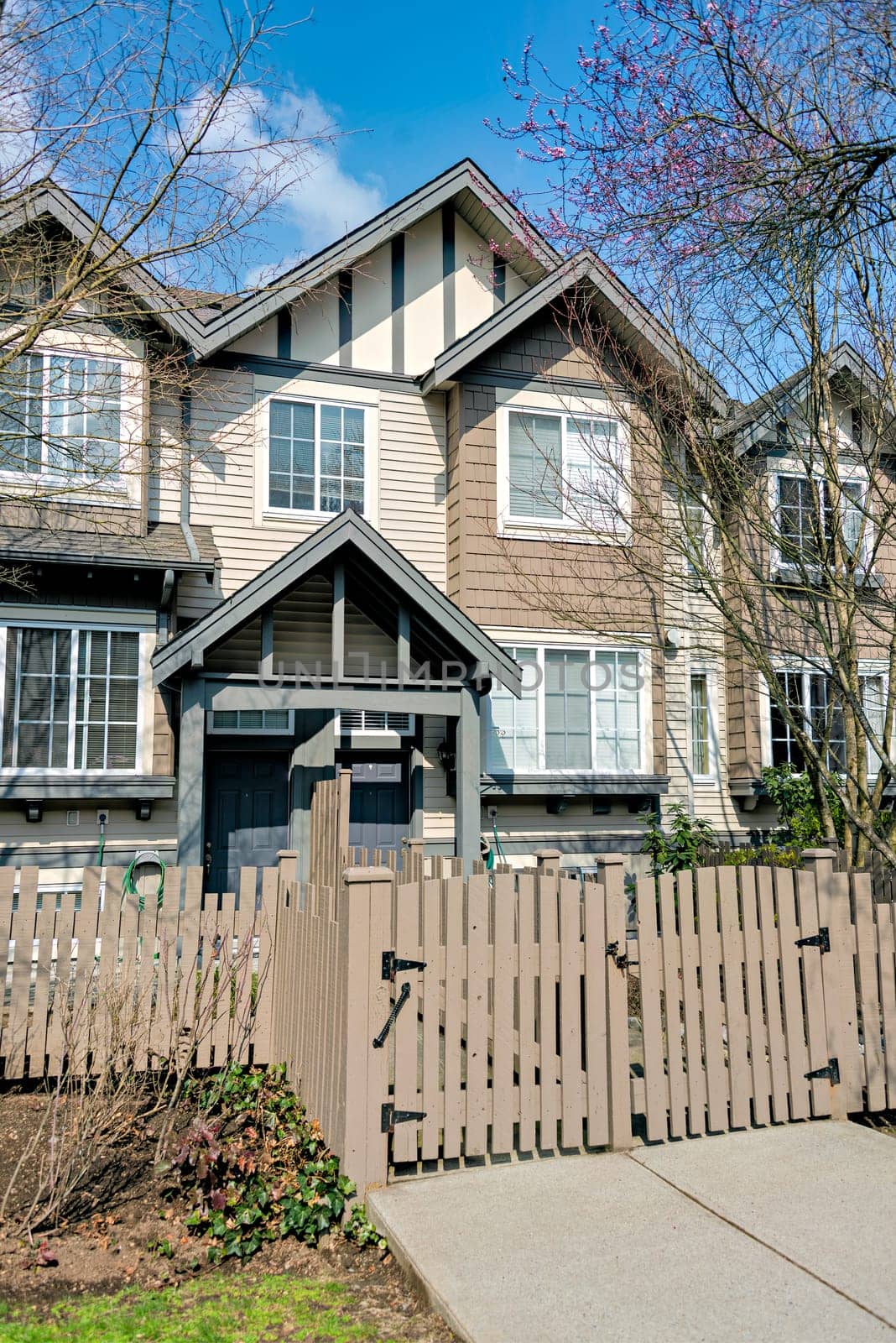 Residential townhouse entrance with wooden fence in front on early sprint day in Vancouver, Canada