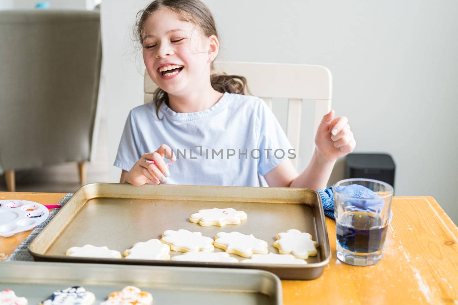 A heartwarming scene of a little girl carefully writing 'Sorry' on sugar cookies with food coloring, the cookies beautifully flooded with white royal icing.