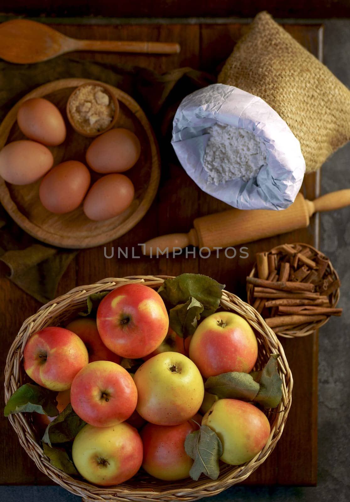 Apples and cinnamon, flour and eggs are used in baking. Ingredients for making homemade apple pie on dark rustic background, top view. Classic autumn dessert by aprilphoto