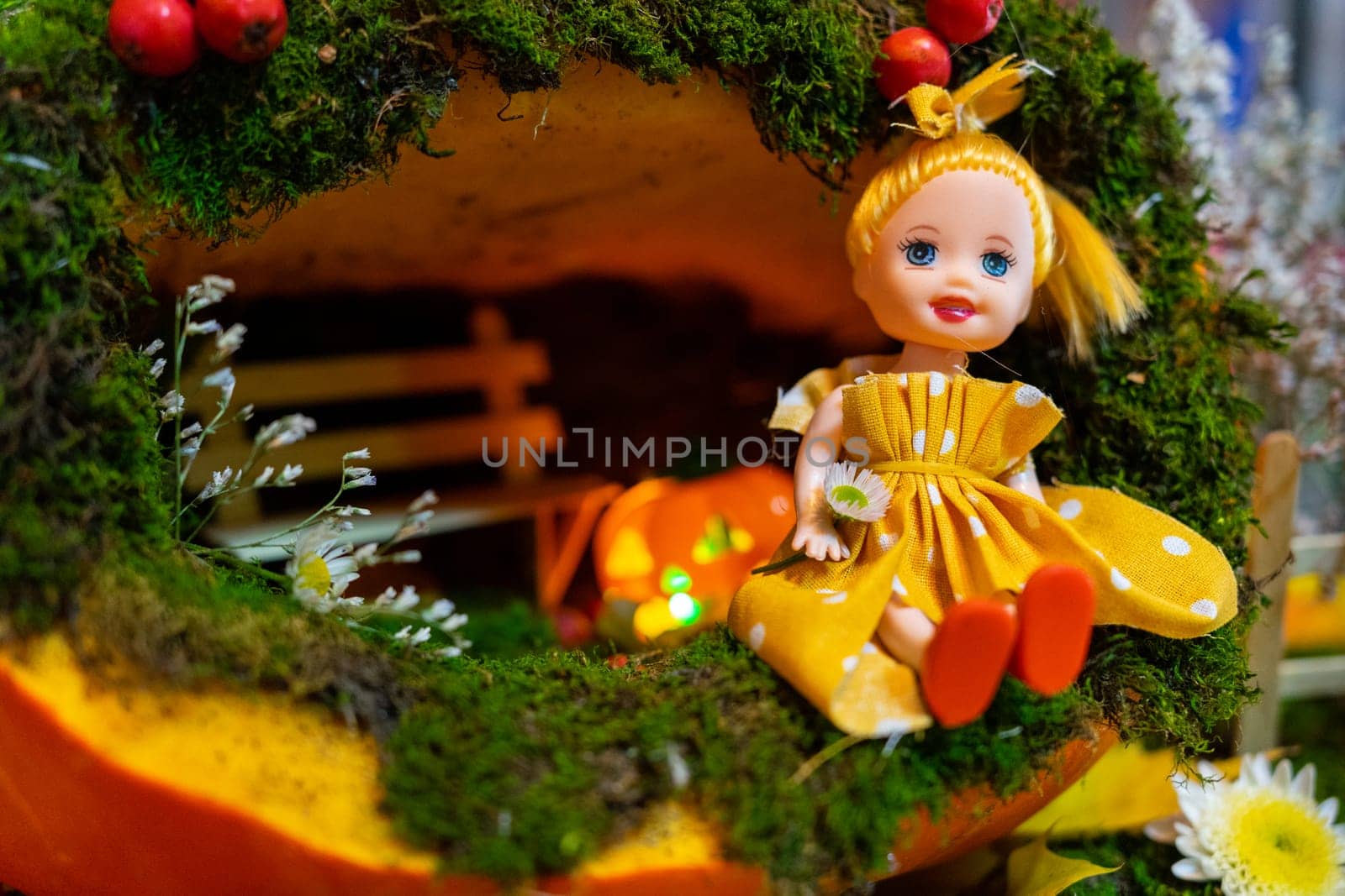 A small doll in a fairy house made of squash.