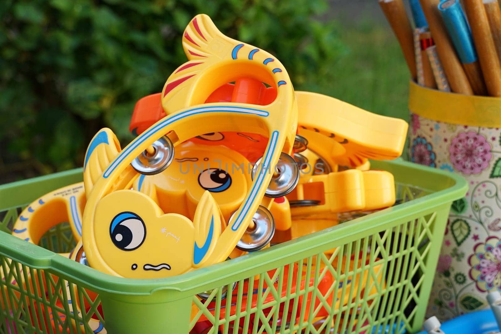 Children's toys in a green plastic basket.