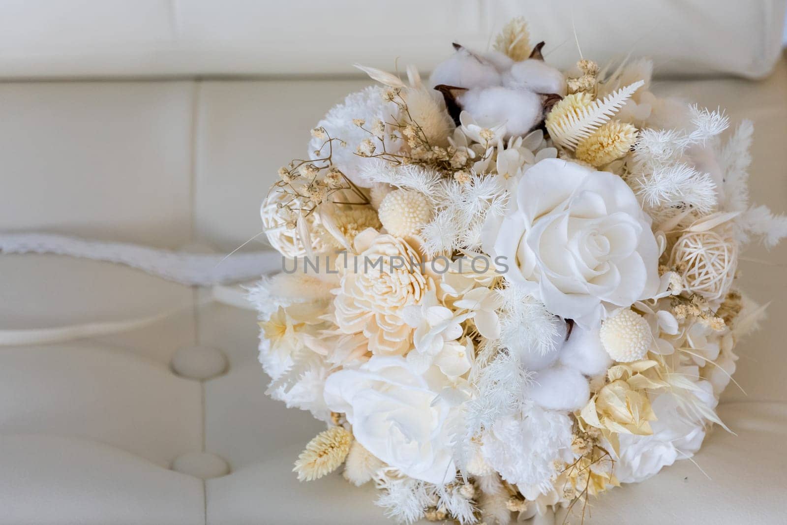 A tender bouquet of the bride in pastel colors on a leather sofa.
