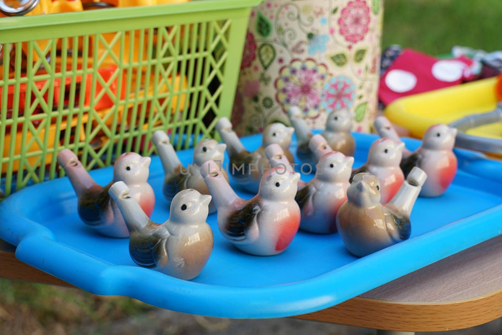 Many children's ceramic whistles in the shape of a bird on a tray.