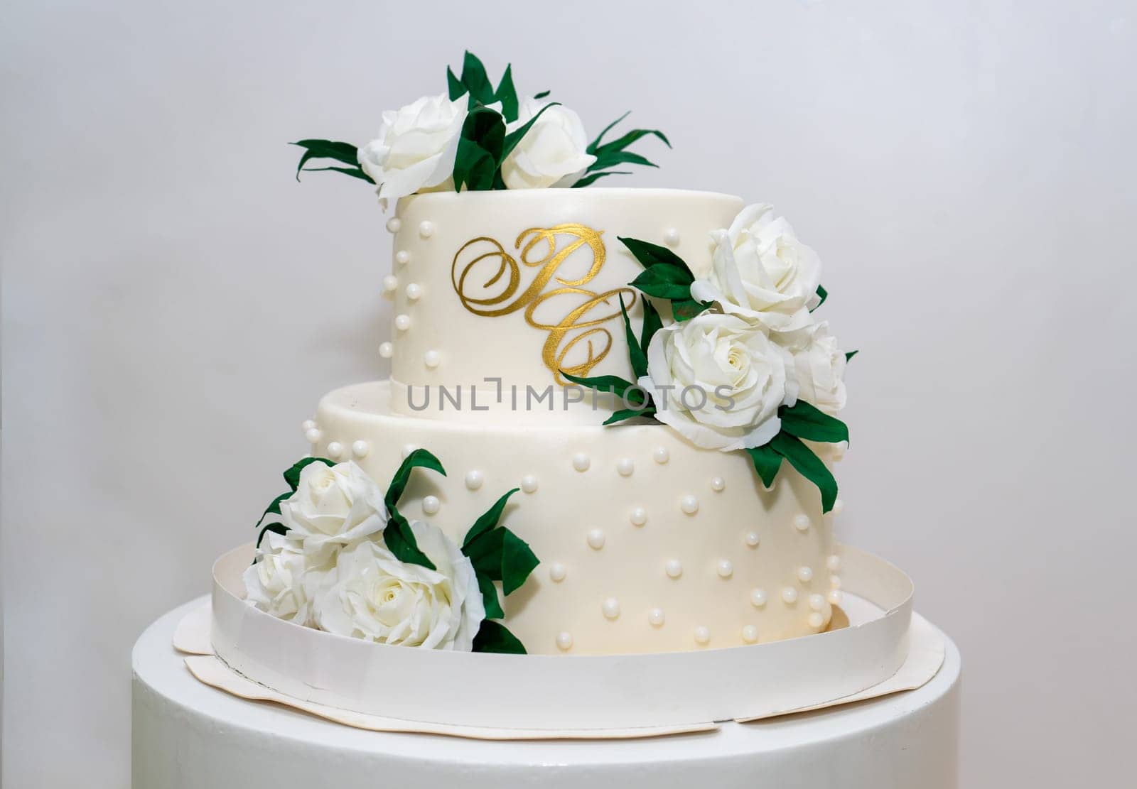 Two-tiered white wedding cake decorated with white roses by Serhii_Voroshchuk