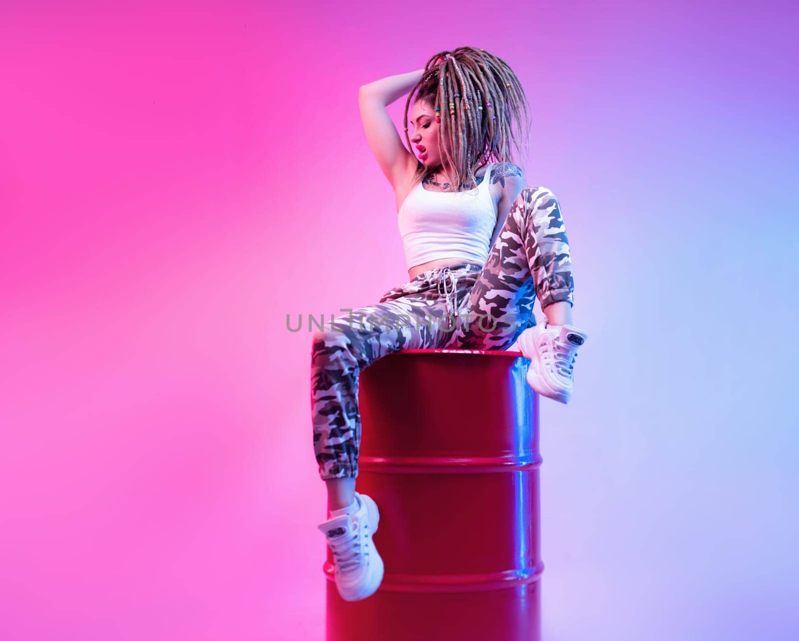 sexy girl with braided dreadlocks on her head in neon light on light background copy paste