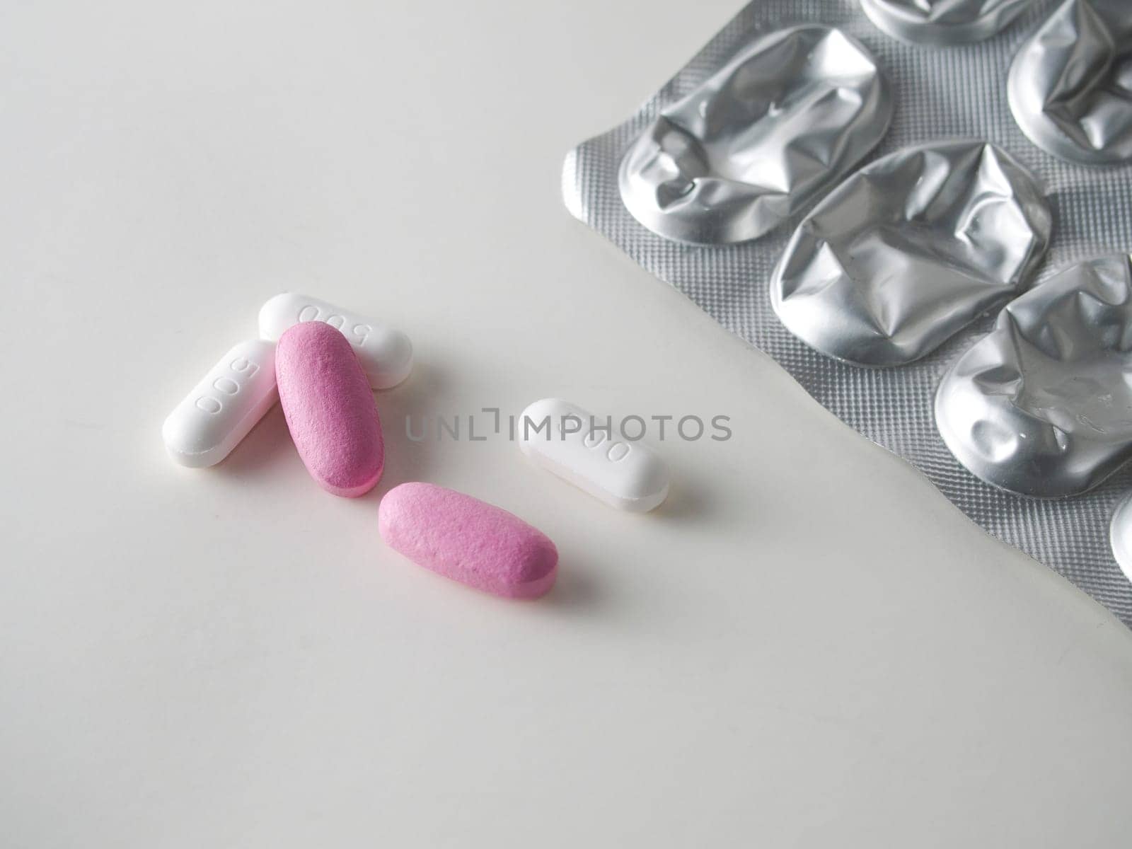 multicolored medical pills and packs of pills on a white table.