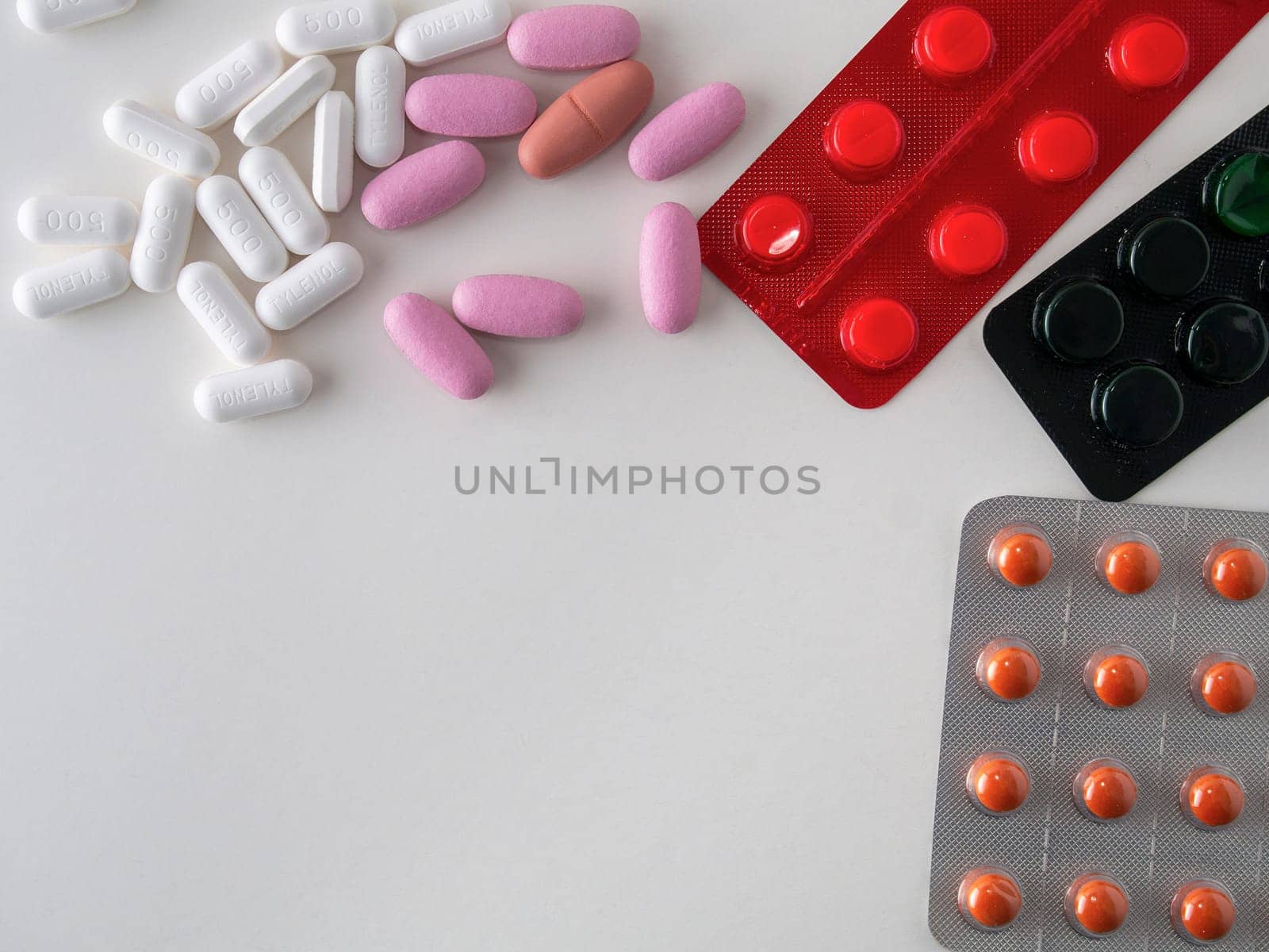 multicolored medical pills and packs of pills on a white table.