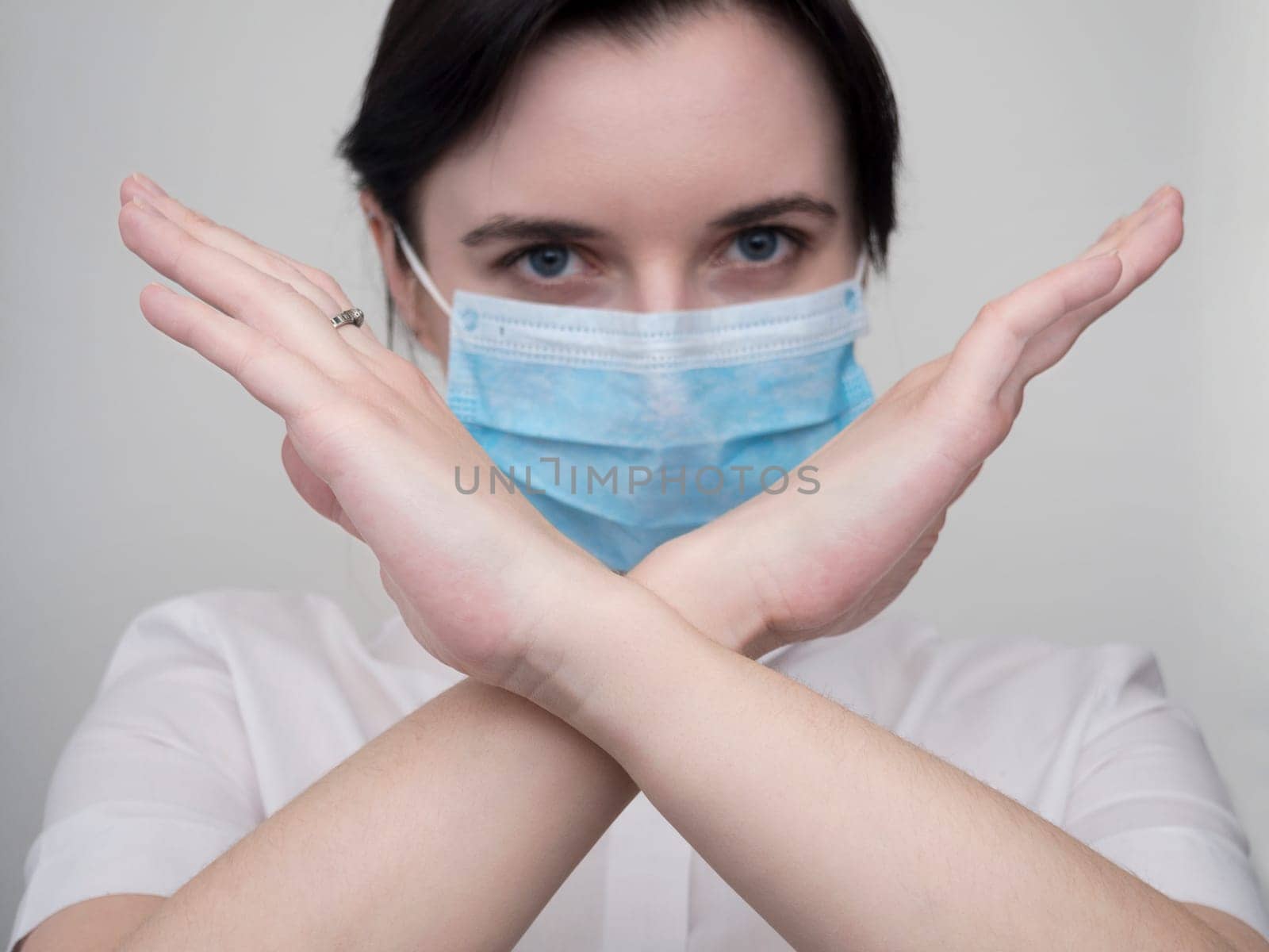 Masked woman makes stopping hand gesture. Stop coronavirus or covid 19 outbreak concept