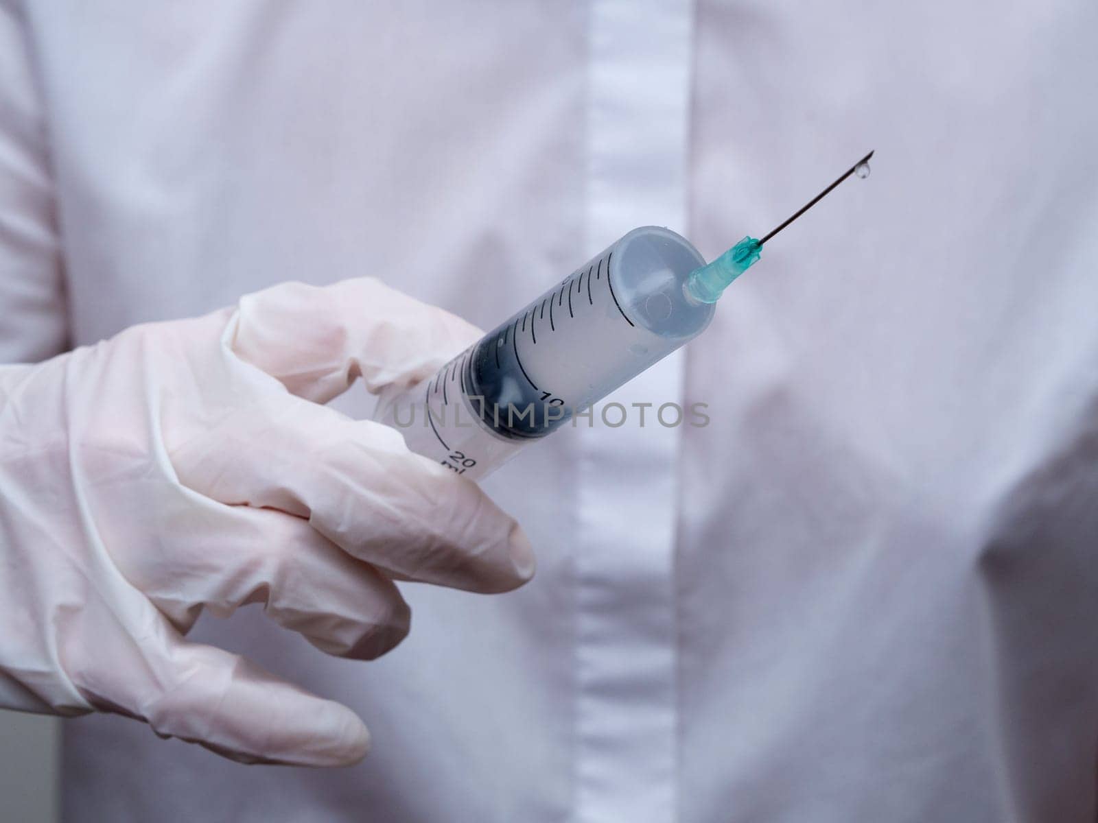 doctor holding a syringe in his hand. Woman in medical mask and gloves holds a syringe with medicine