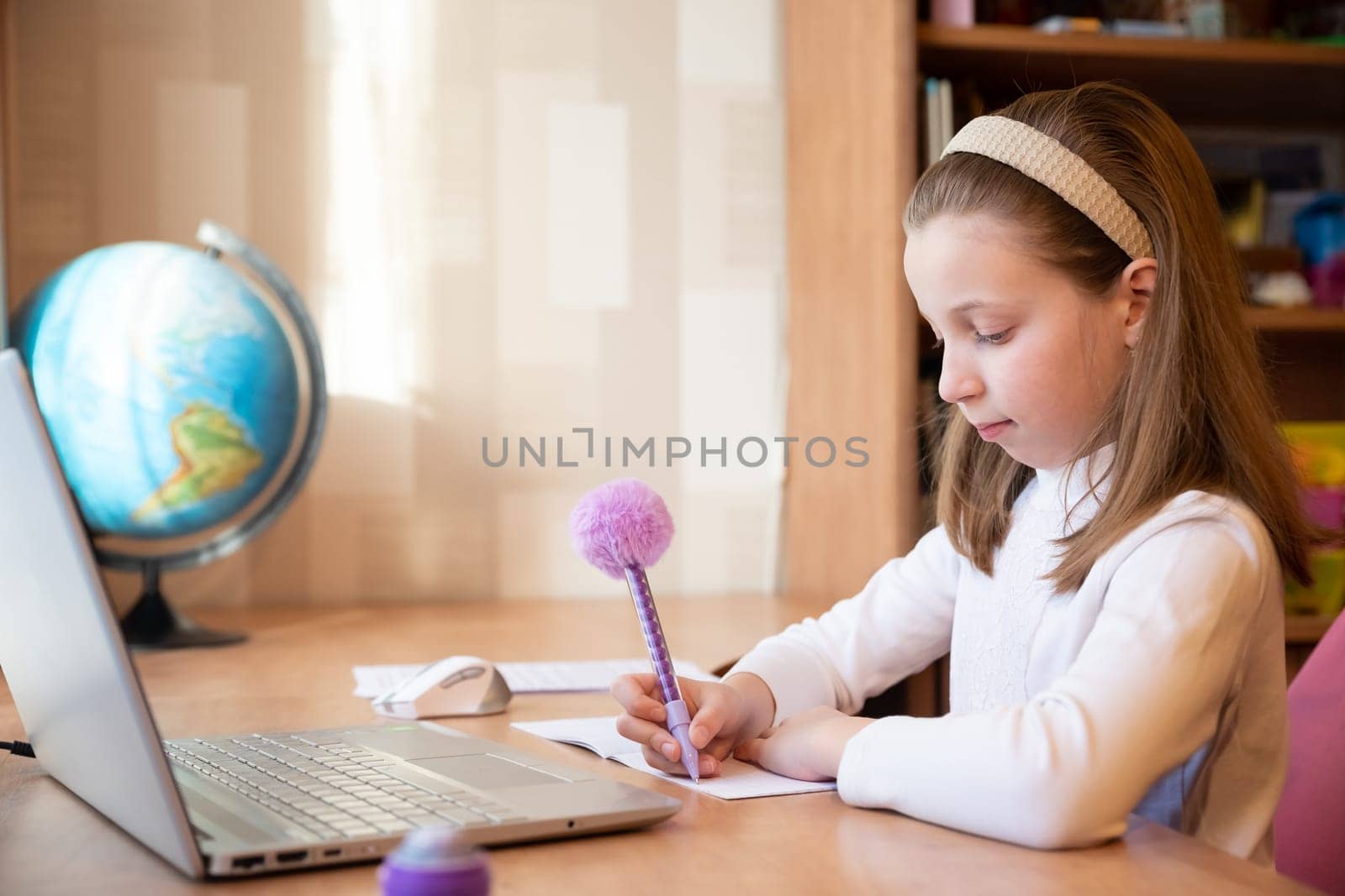 Online education of children. Girl schoolgirl teaches a lesson online using a laptop video chat call conference with a teacher at home.