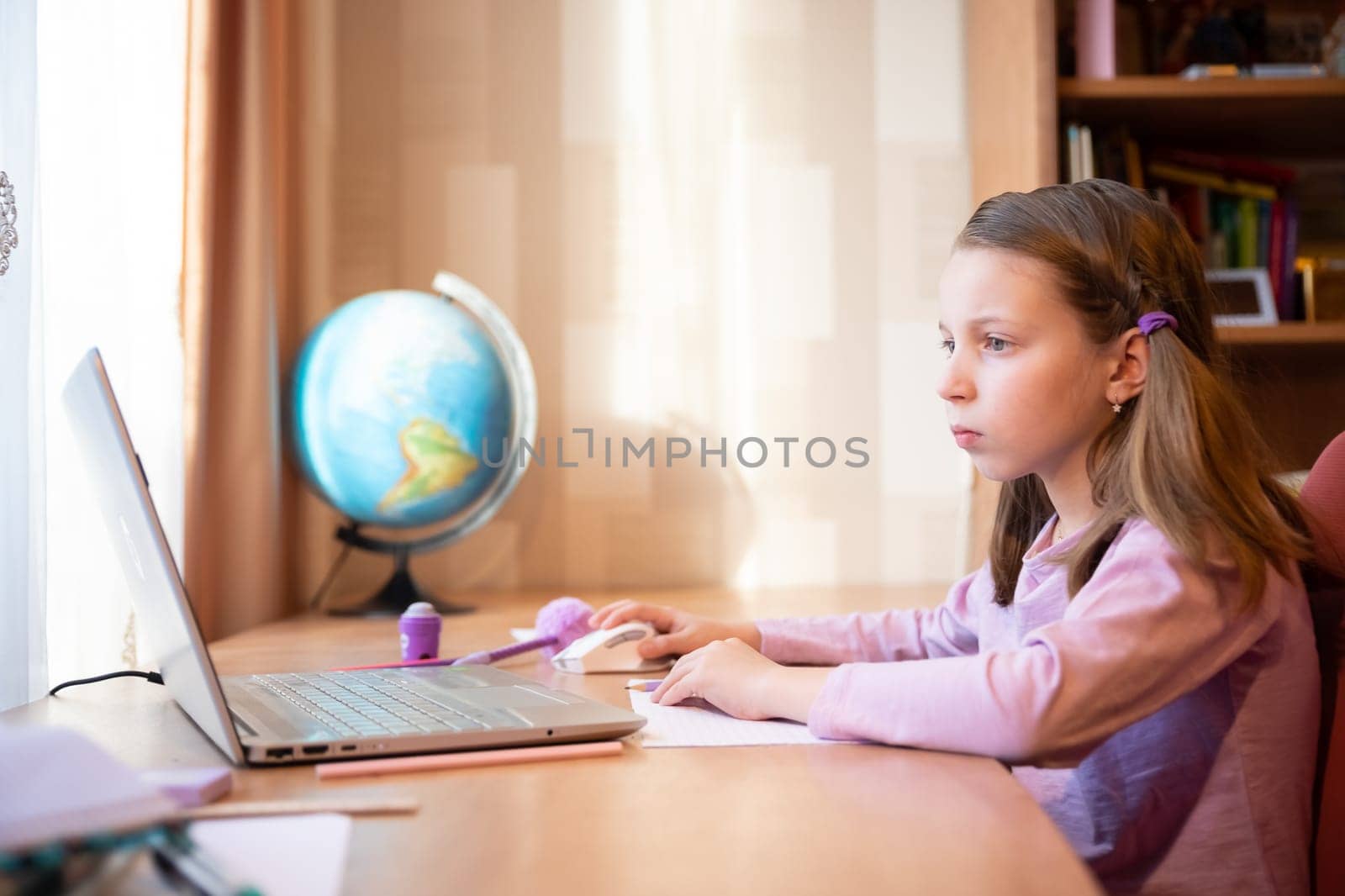 Online education of children. Girl schoolgirl teaches a lesson online using a laptop video chat call conference with a teacher at home.