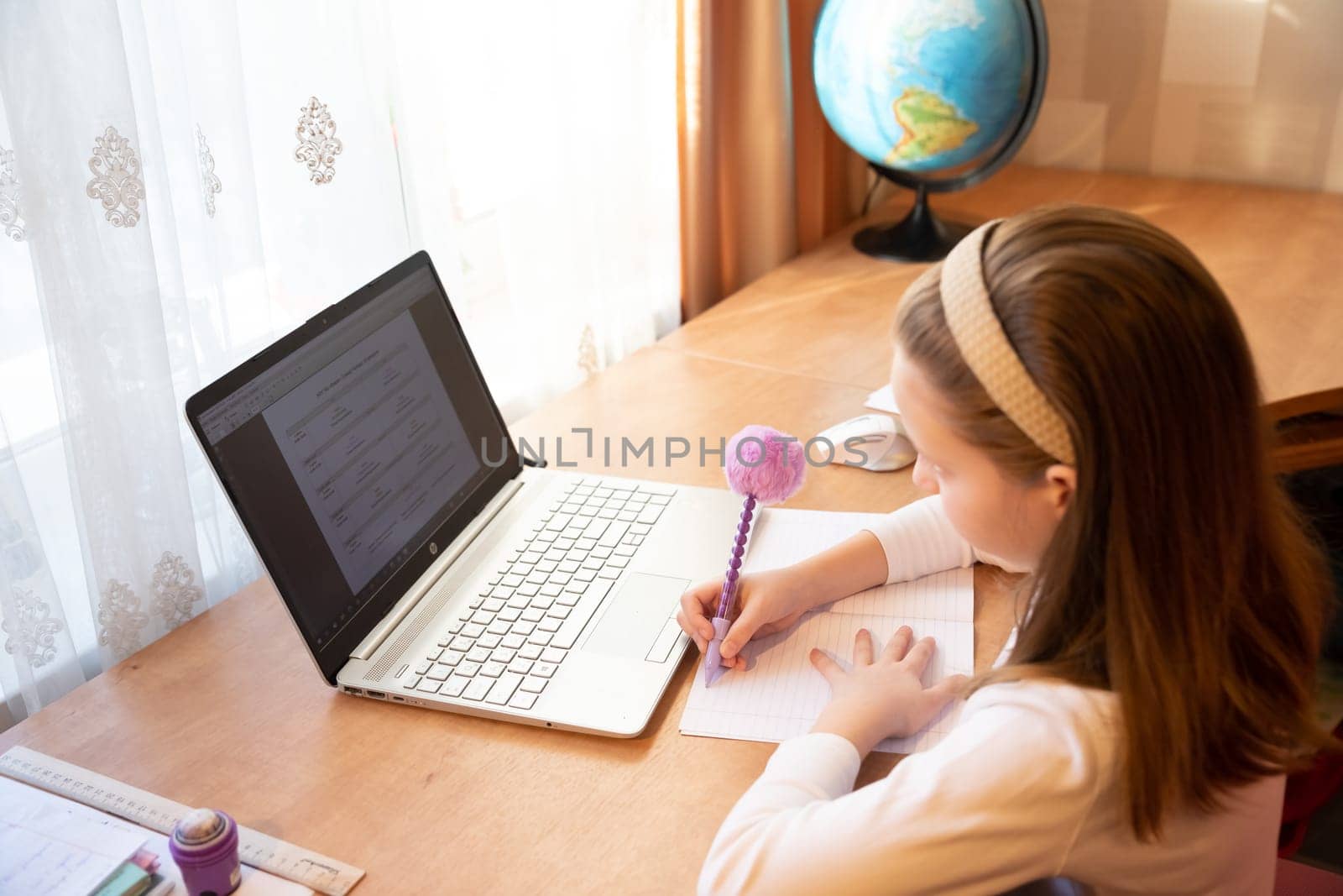 Online education of children. Girl schoolgirl teaches a lesson online using a laptop video chat call conference with a teacher at home.studying, participating in online conference, sitting at desk by YuliaYaspe1979