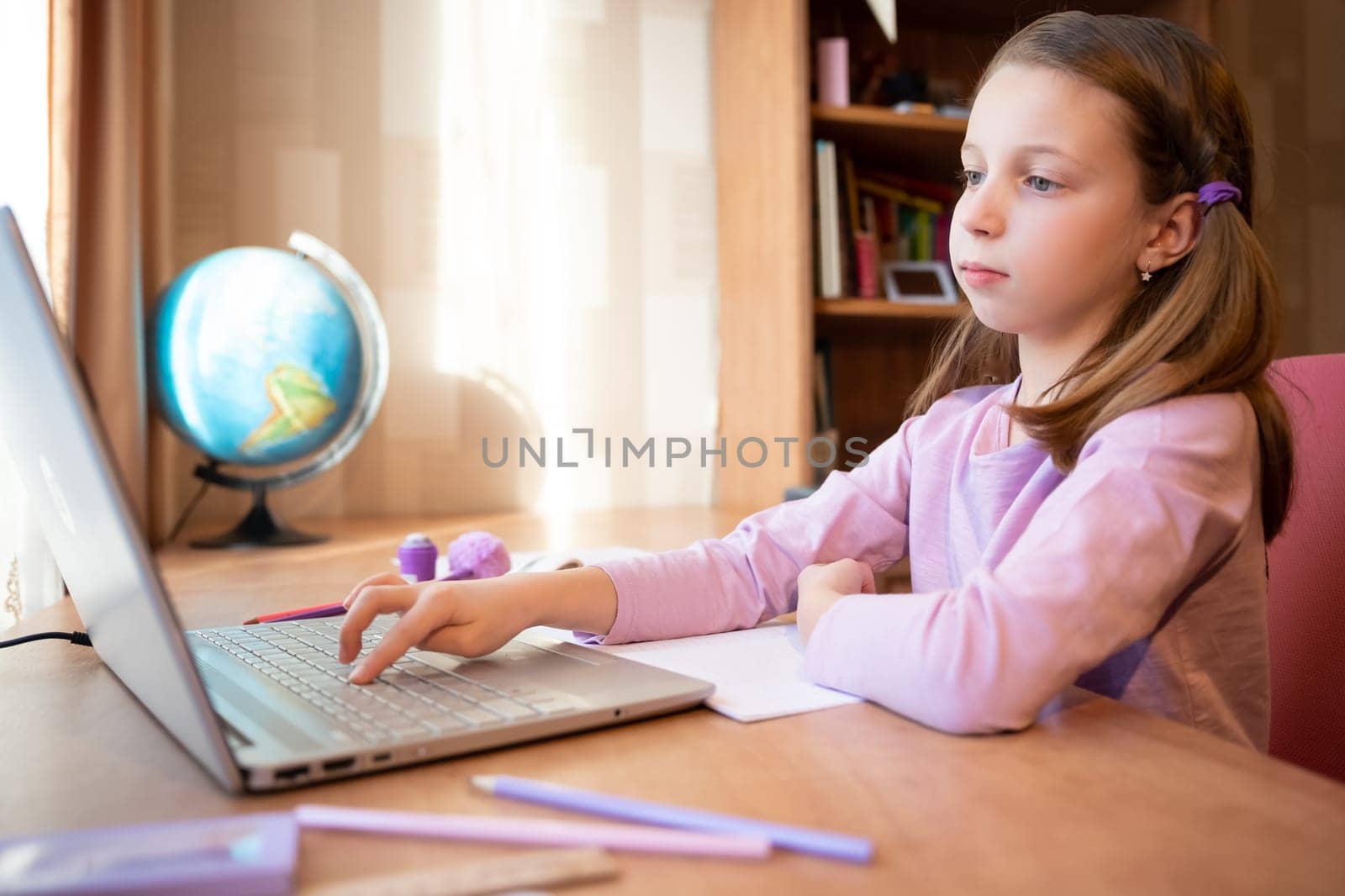 Online education of children. Girl schoolgirl teaches a lesson online using a laptop video chat call conference with a teacher at home.studying, participating in online conference, sitting at desk by YuliaYaspe1979