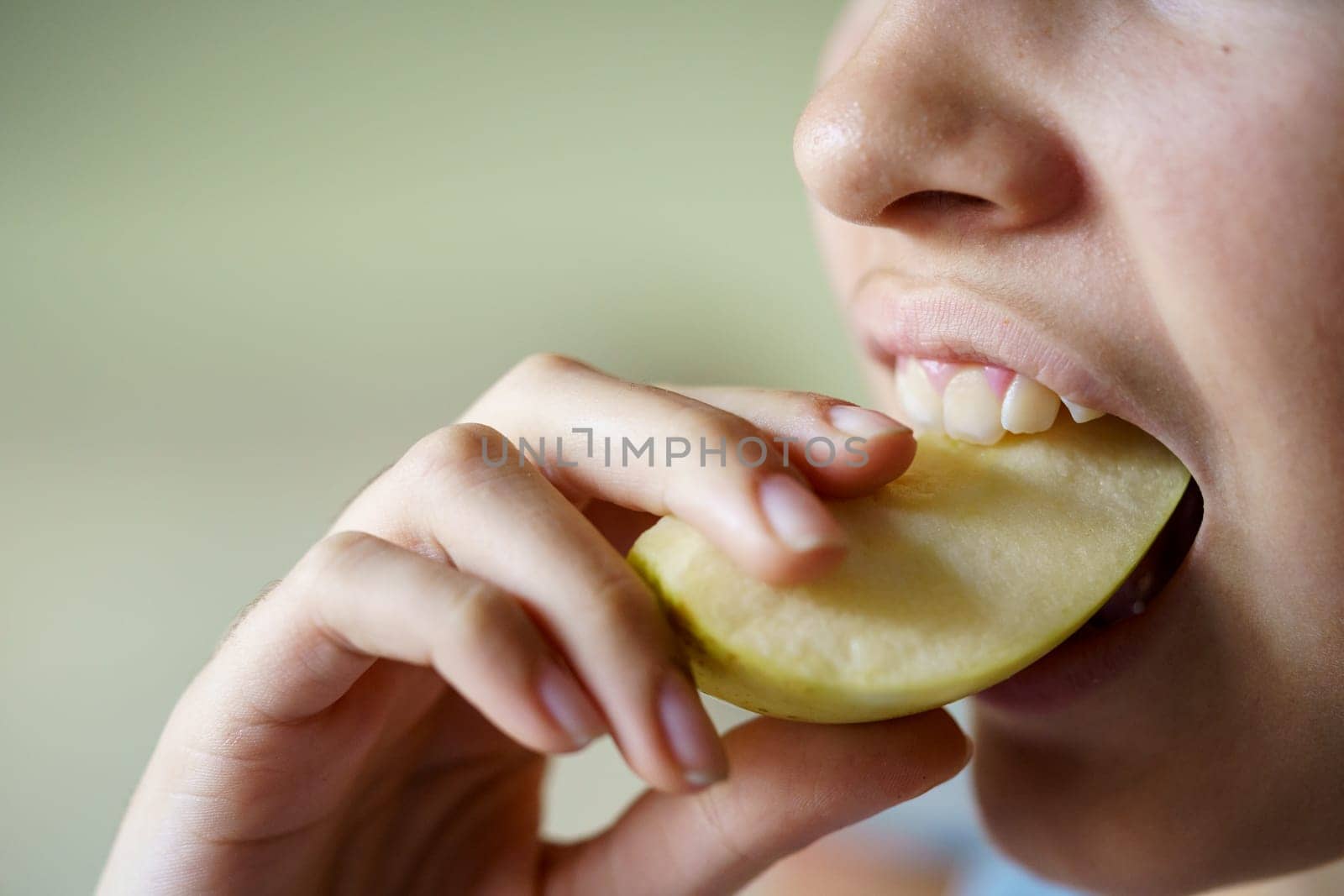 Closeup of anonymous teenage girl eating fresh apple slice at home