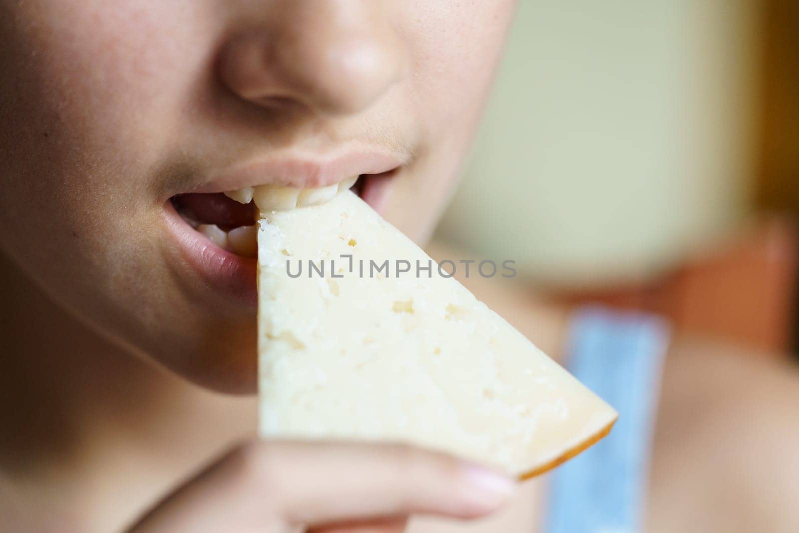 Crop young girl eating yummy cheese slice at home by javiindy