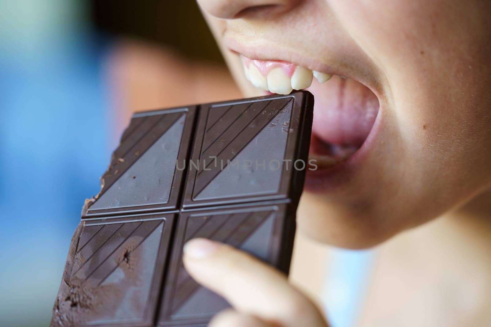 Closeup of anonymous young girl with mouth wide open about to eat chocolate bar at home