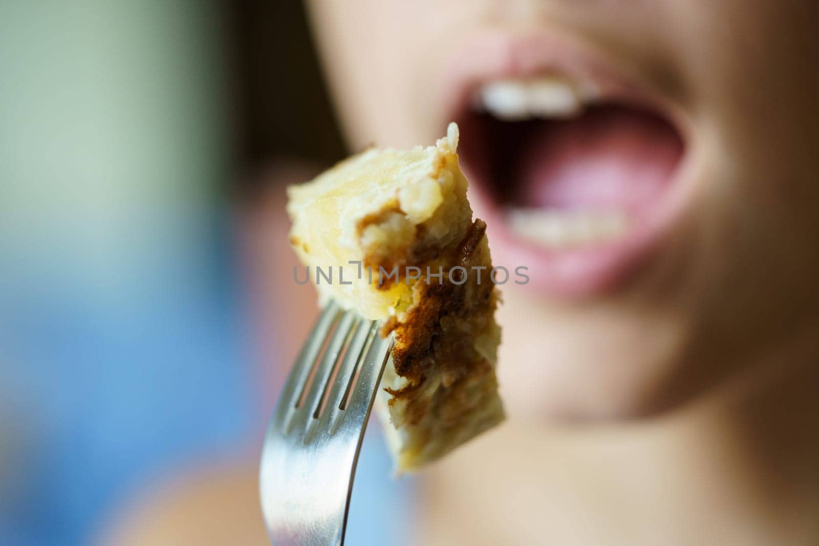 Anonymous teenage girl about to eat fresh potato omelette from fork by javiindy