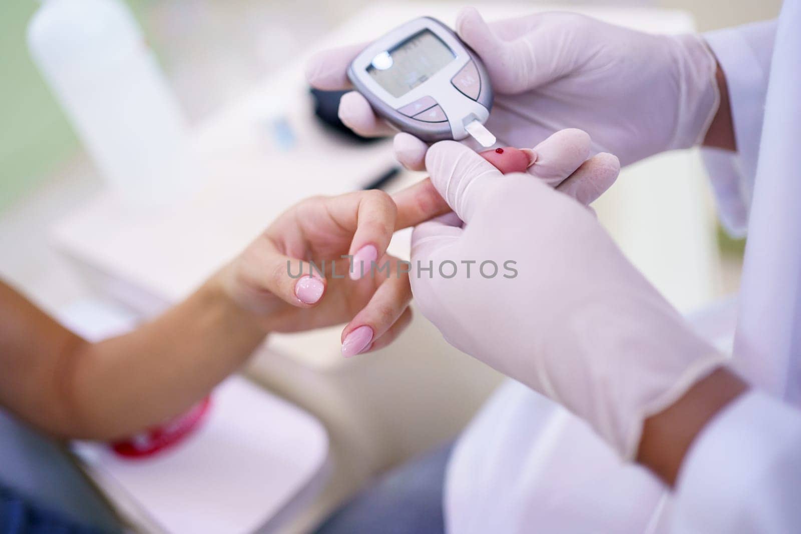 From above of crop unrecognizable male doctor hands checking blood sugar level of patient in hospital