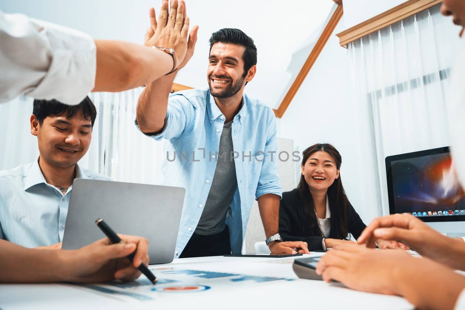 Analyst team leader celebrate and high five together with his colleague after successful data analysis meeting using FIntech software power with business intelligence or BI dashboard. Prudent