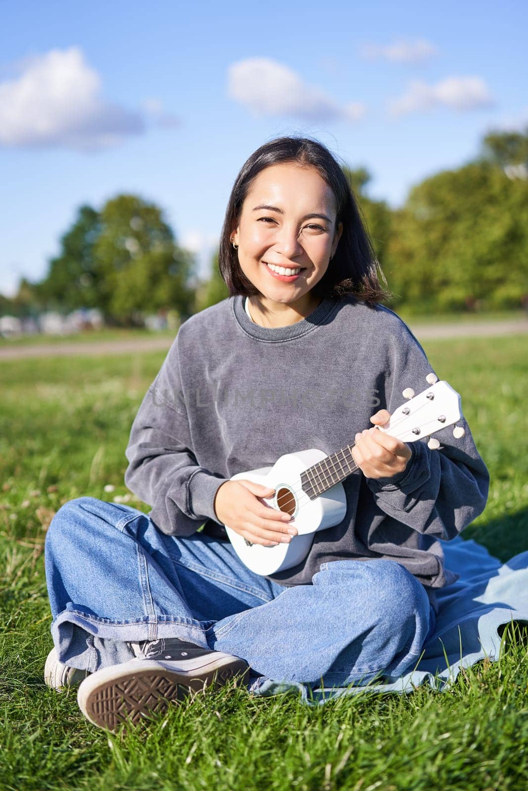 Positive hipster asian girl, playing ukulele and making faces, singing and feeling happy by Benzoix